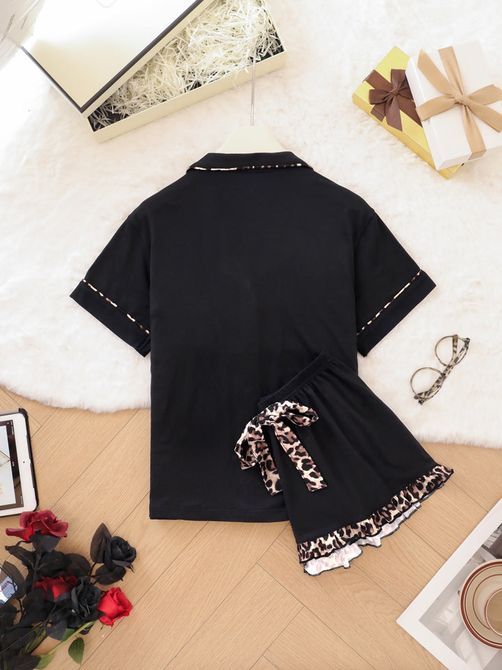 Black pajamas with leopard print details on a wooden floor.