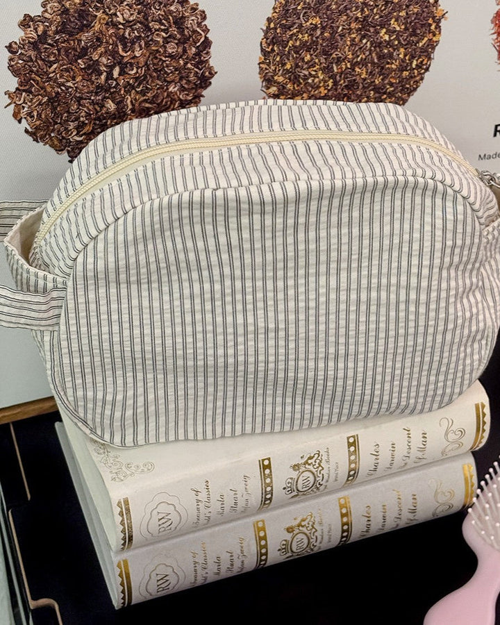 Striped fabric bag on top of books with a hairbrush in the foreground