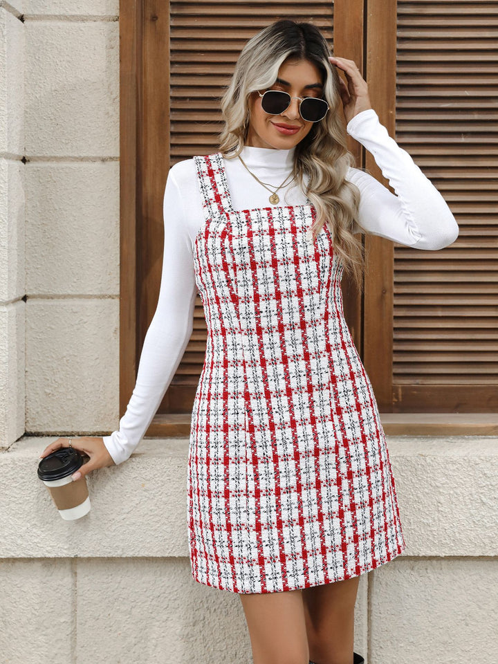 Woman wearing a red and white checkered dress holding a coffee cup against a stone wall.