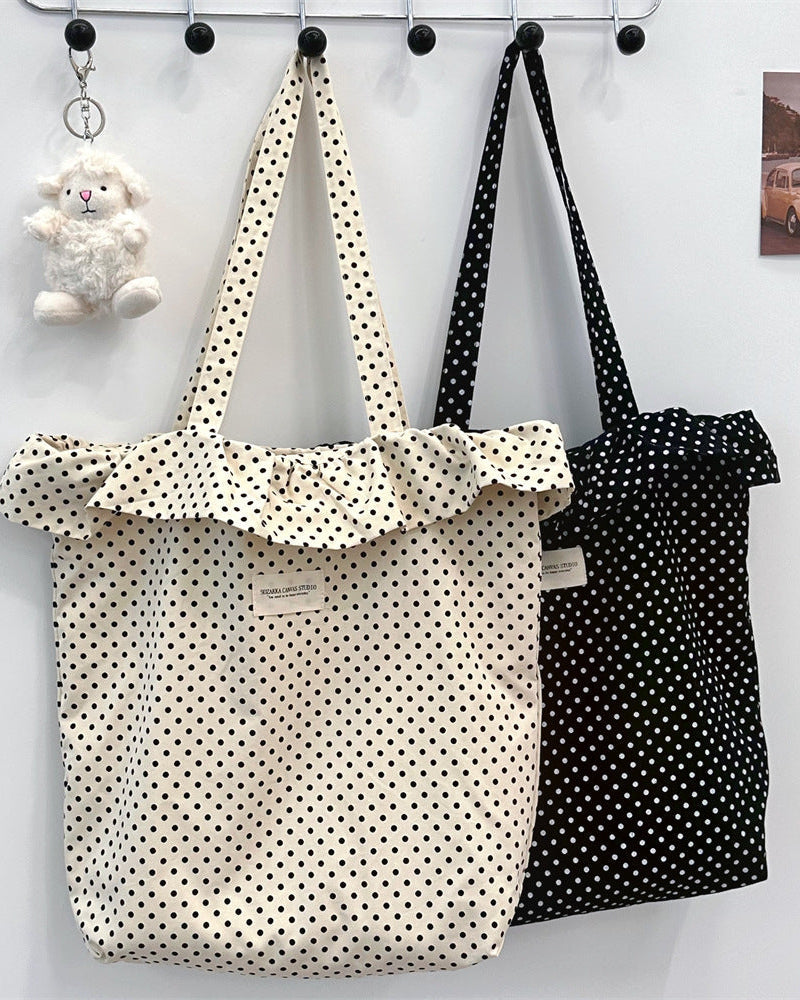 Two polka dot bags hanging on a rack with a small plush toy in the background.