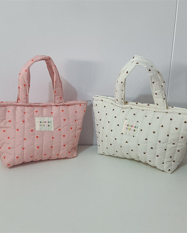 Two quilted handbags with heart patterns on a light gray background