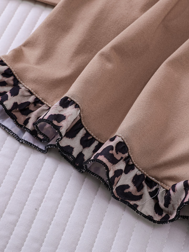 Close-up of a brown fabric with leopard print trim on a white quilted surface