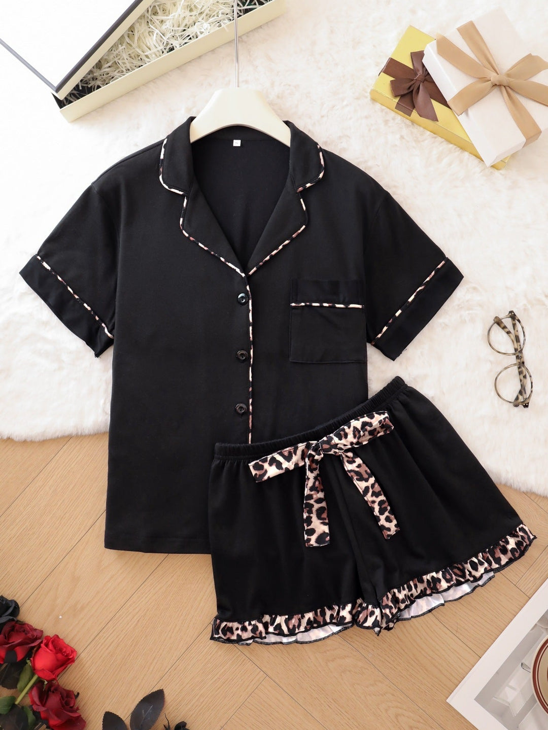 Black pajama set with leopard print trim on a wooden floor.