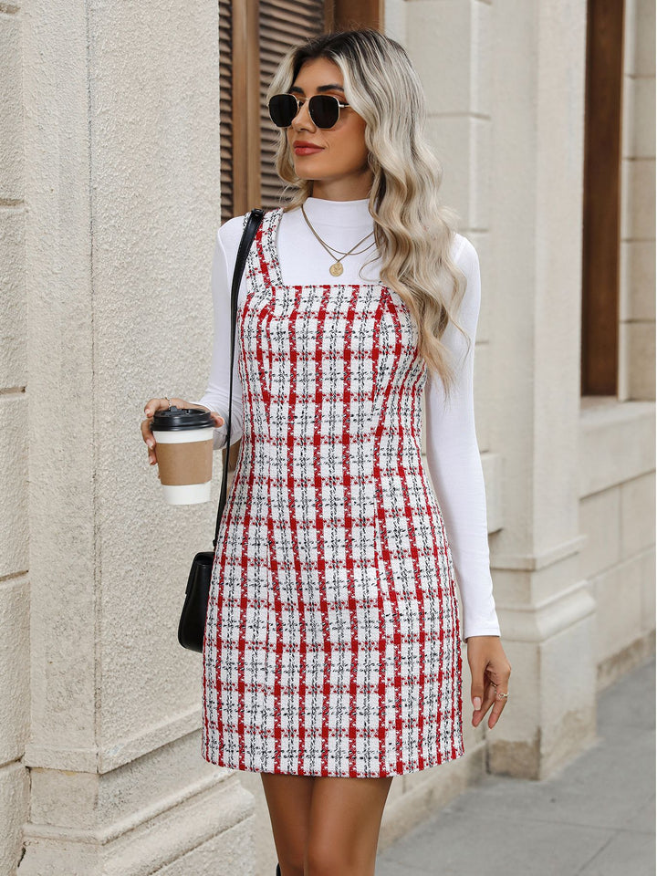 Woman in a red and white checkered dress holding a coffee cup against a building background