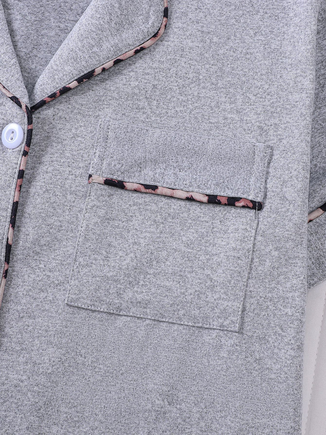 Close-up of a gray garment with floral trim on buttons and pocket.