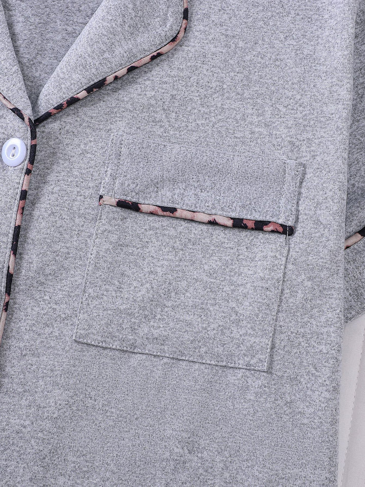 Close-up of a gray garment with floral trim on buttons and pocket.