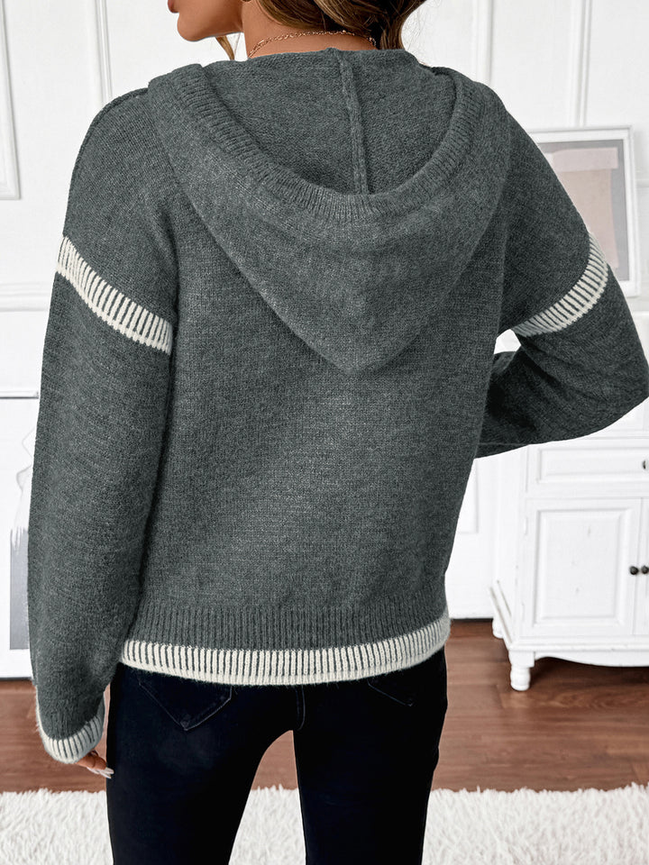 Gray hoodie with white stripes on sleeves and hem, worn by a person indoors.