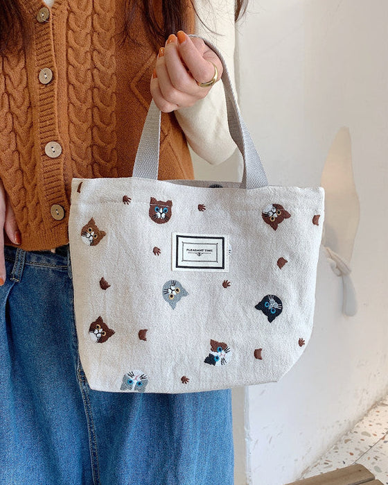 Person holding a white tote bag with bear patterns in an indoor setting