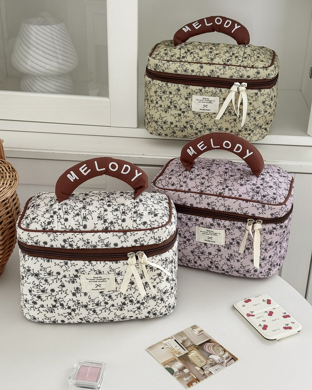 Two floral-patterned beauty cases with 'Melody' branding on a white surface.