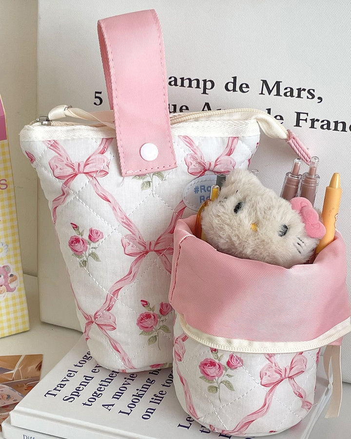 Small fabric bag with a teddy bear toy inside, on top of books.