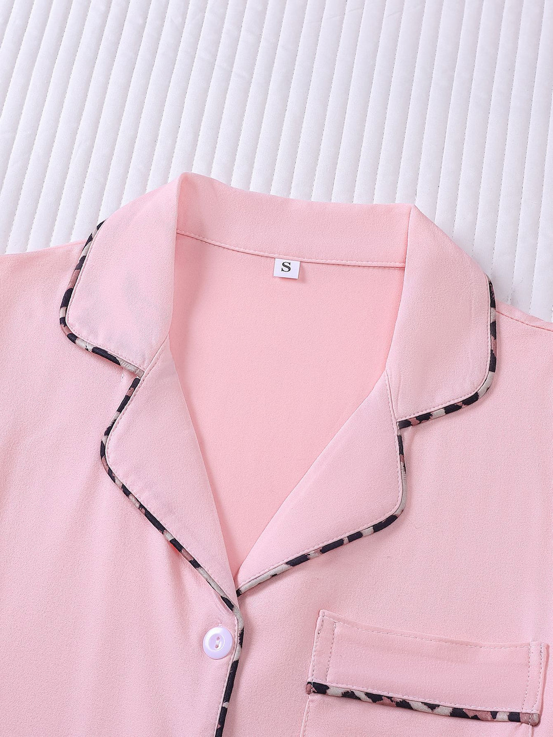 Pink pajama top with black trim on a white background