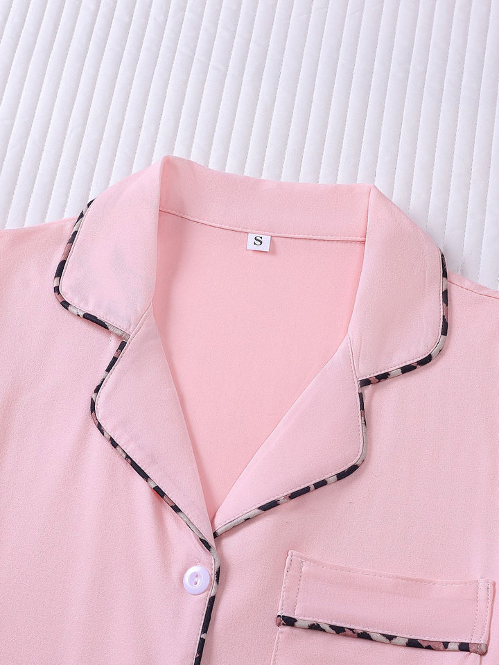 Pink pajama top with black trim on a white background