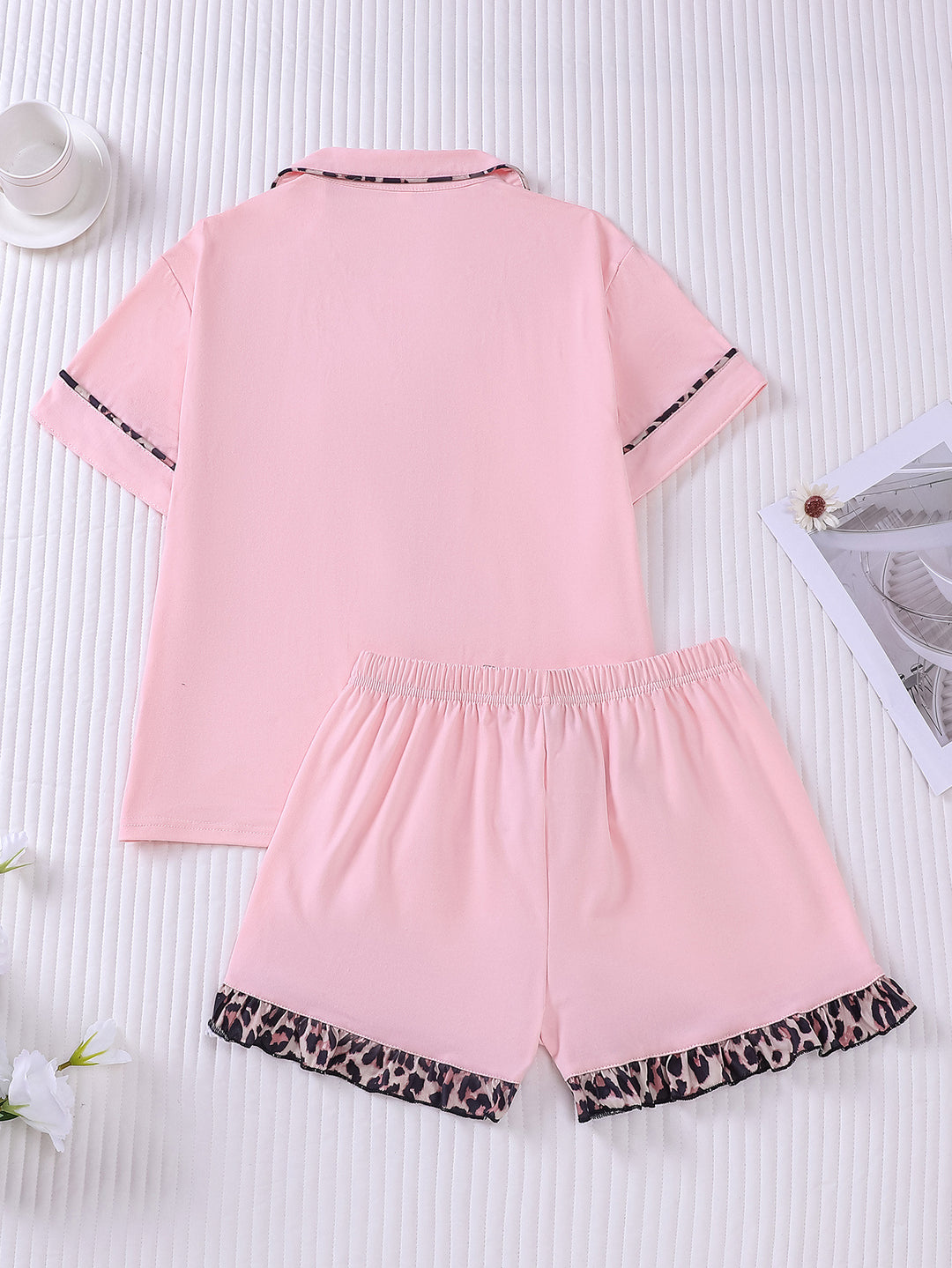 Pink pajama set with leopard print trim on a white background