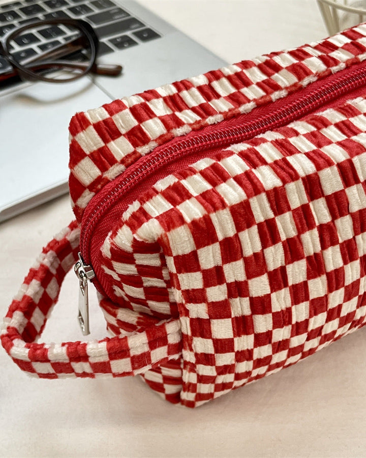 Red and white checkered pouch on a desk with glasses and a laptop.