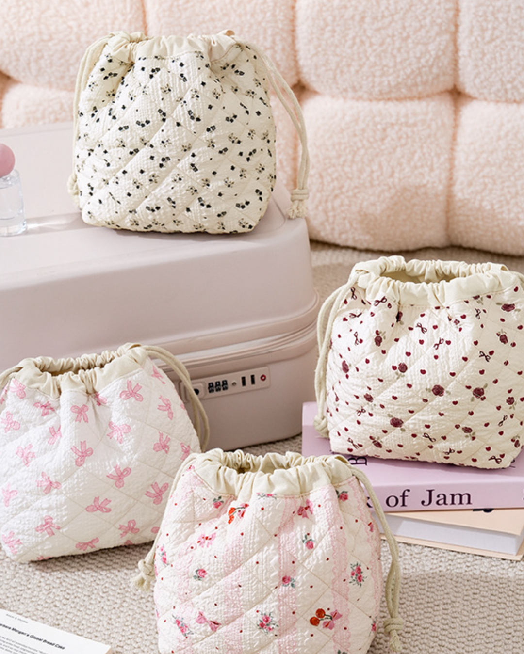 Four floral drawstring bags on a light-colored surface with a pink textured background.