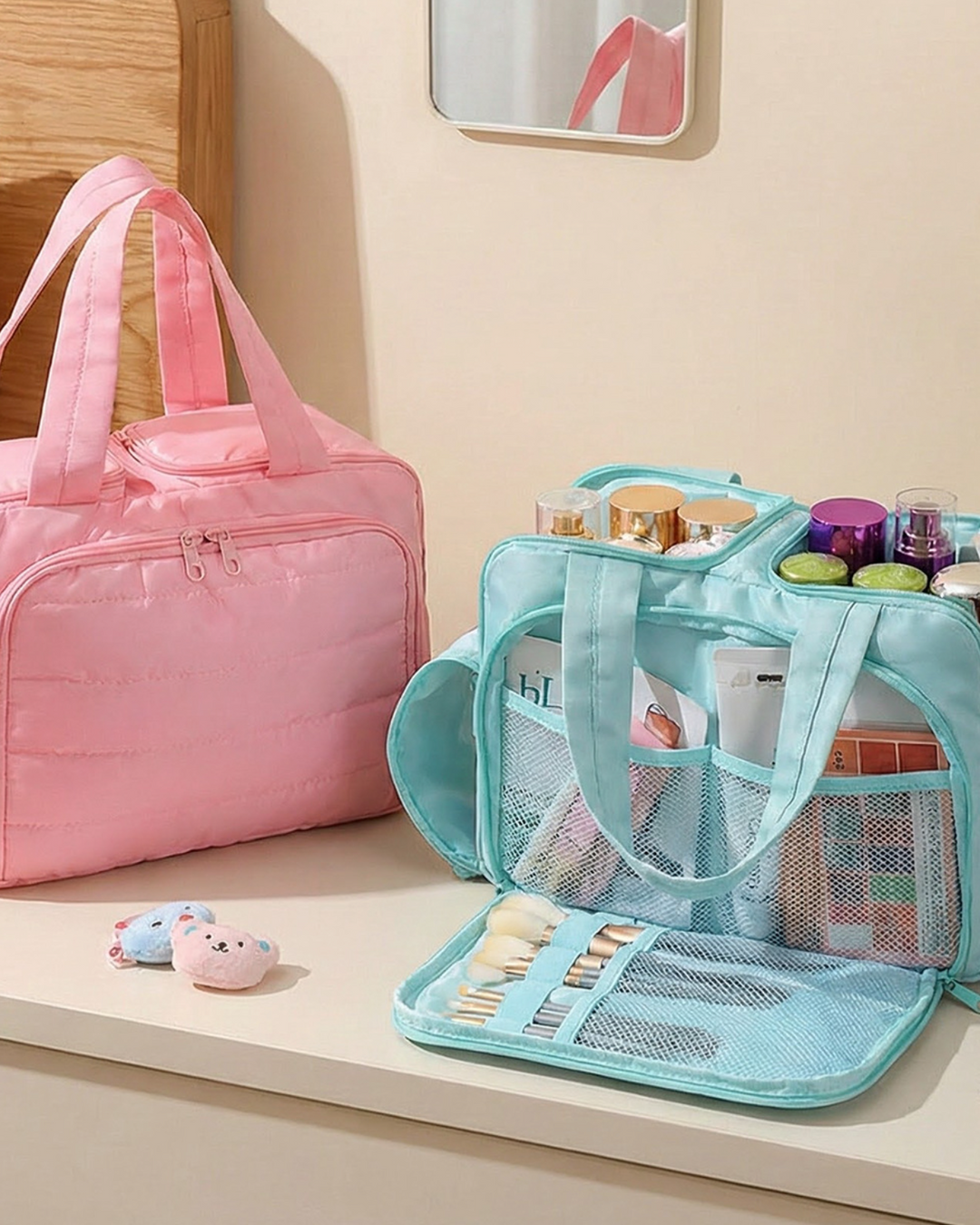 Pink and blue travel bags with cosmetic items on a table.