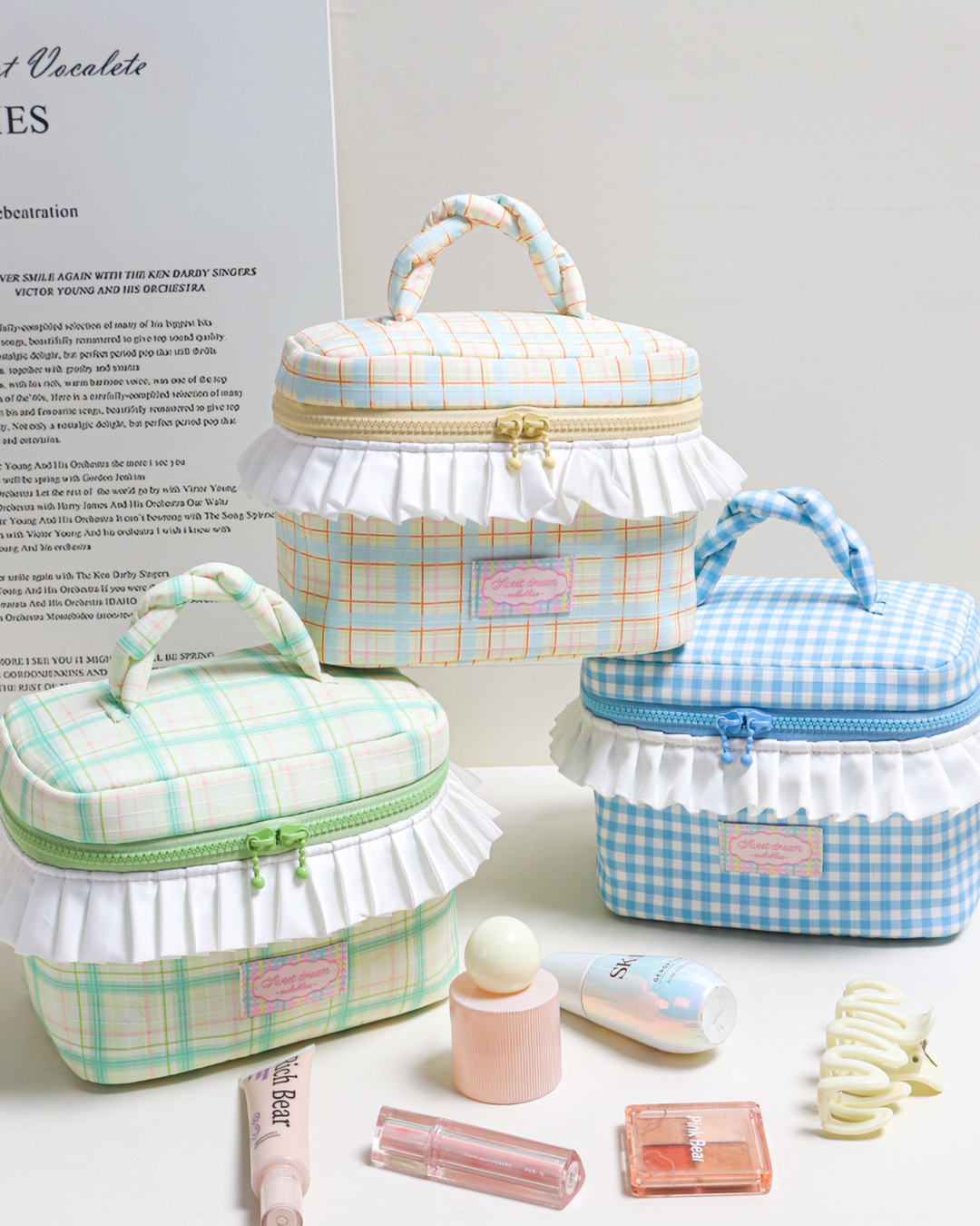 Set of three checkered cosmetic bags with small items on a light surface.