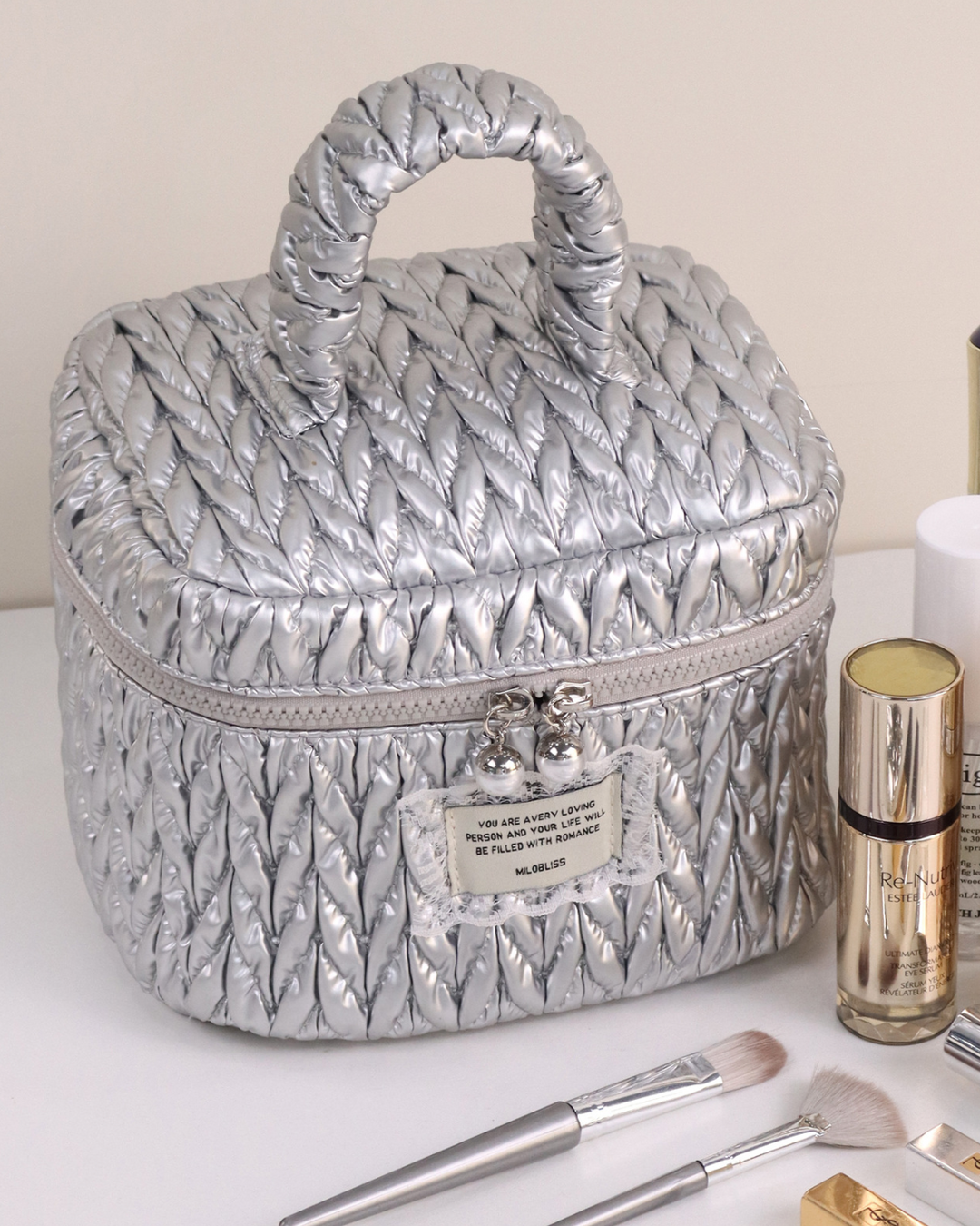 Silver quilted makeup case with cosmetic products on a white background