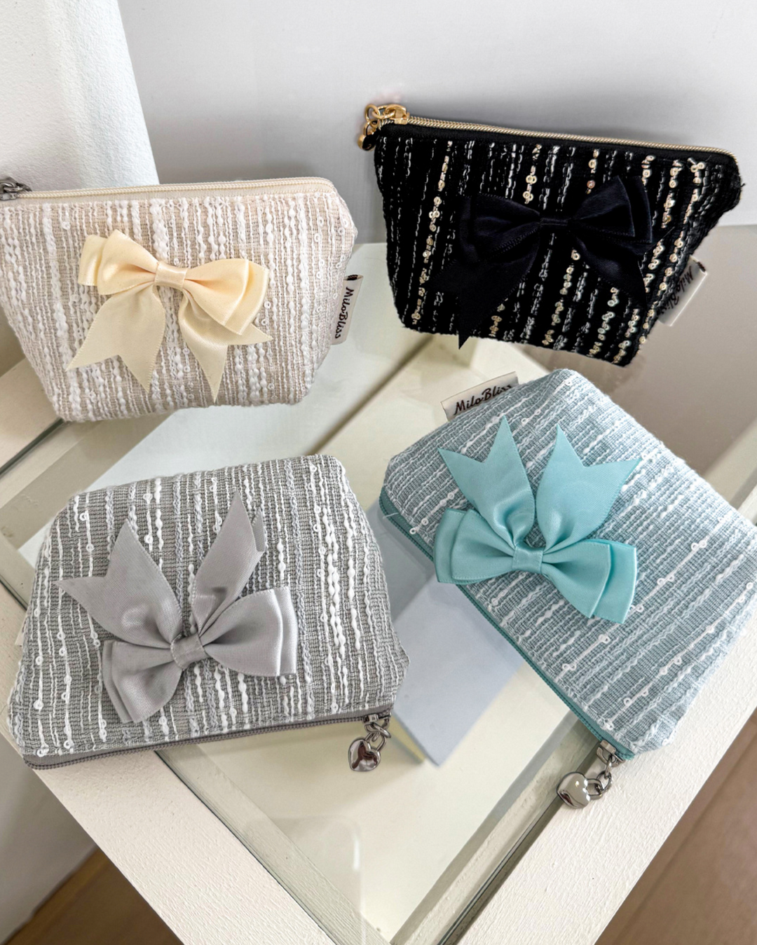 Four small pouches with decorative bows on a white surface