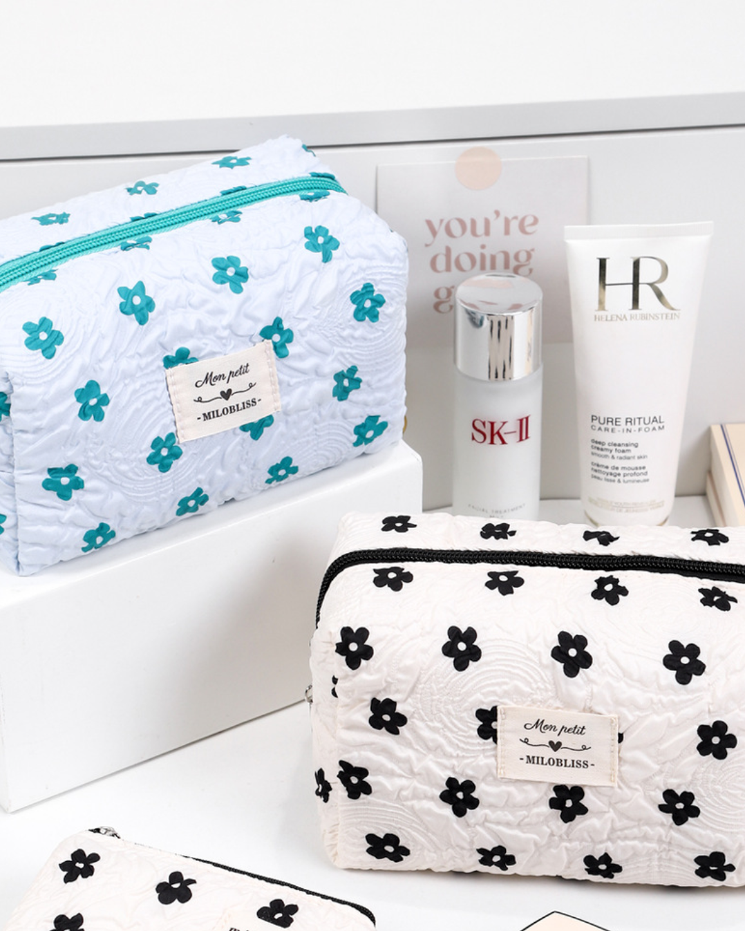 Two floral-patterned cosmetic bags with skincare products on a white background