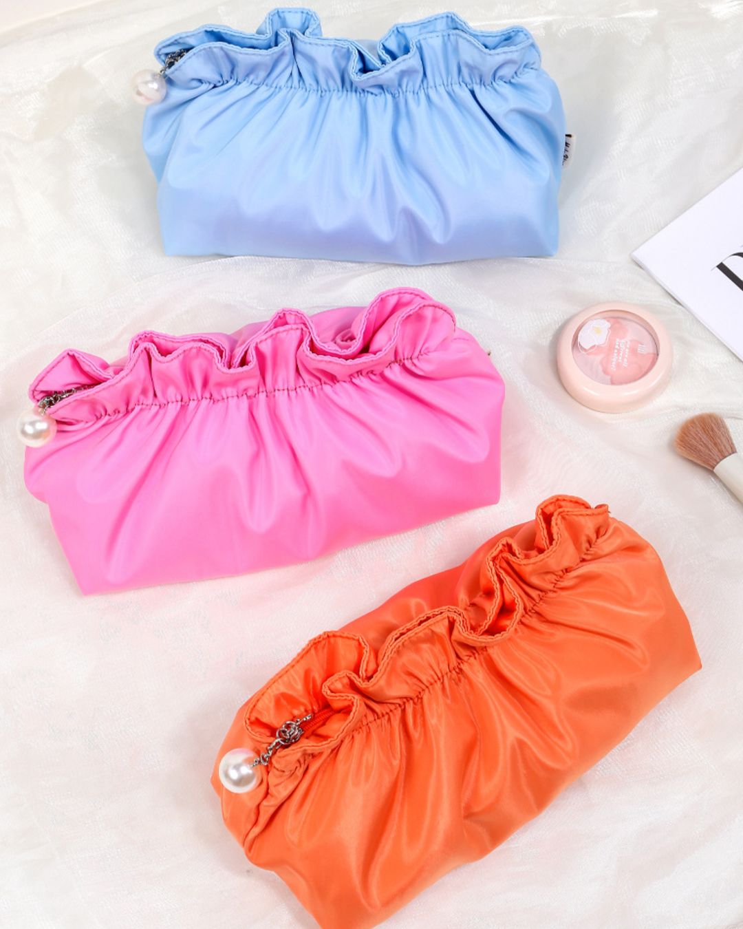 Three colorful fabric bags in blue, pink, and orange on a light background.