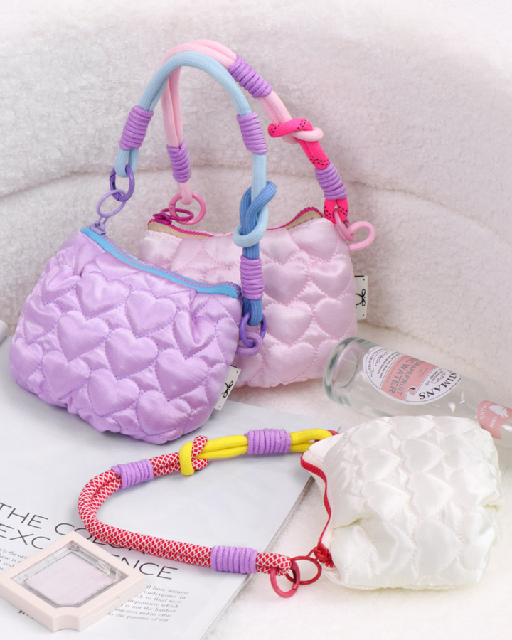 Pink textured bag with colorful handle on a light gray surface