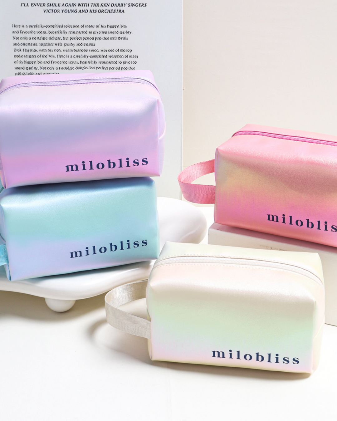 Pastel gradient beauty bags with 'milobliss' branding on a white surface.