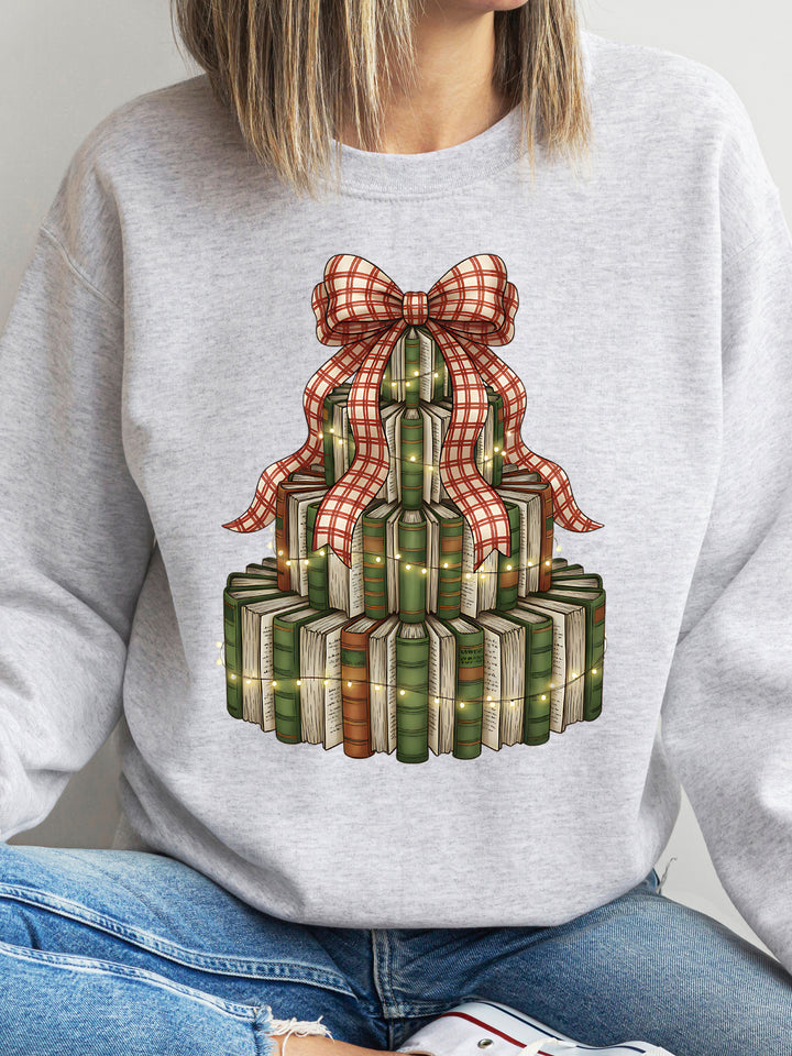 Gray sweatshirt with a design of books stacked with a bow on top, worn by a person.