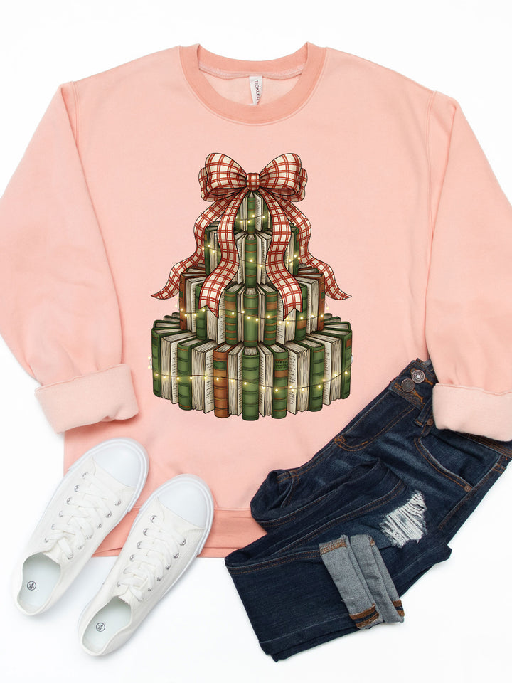 Pink sweatshirt with a festive design, white sneakers, and dark jeans on a white background