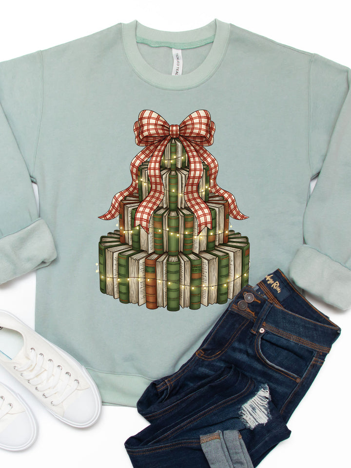 Light blue sweatshirt with Christmas tree and gift box design, paired with jeans and white sneakers on a white background.
