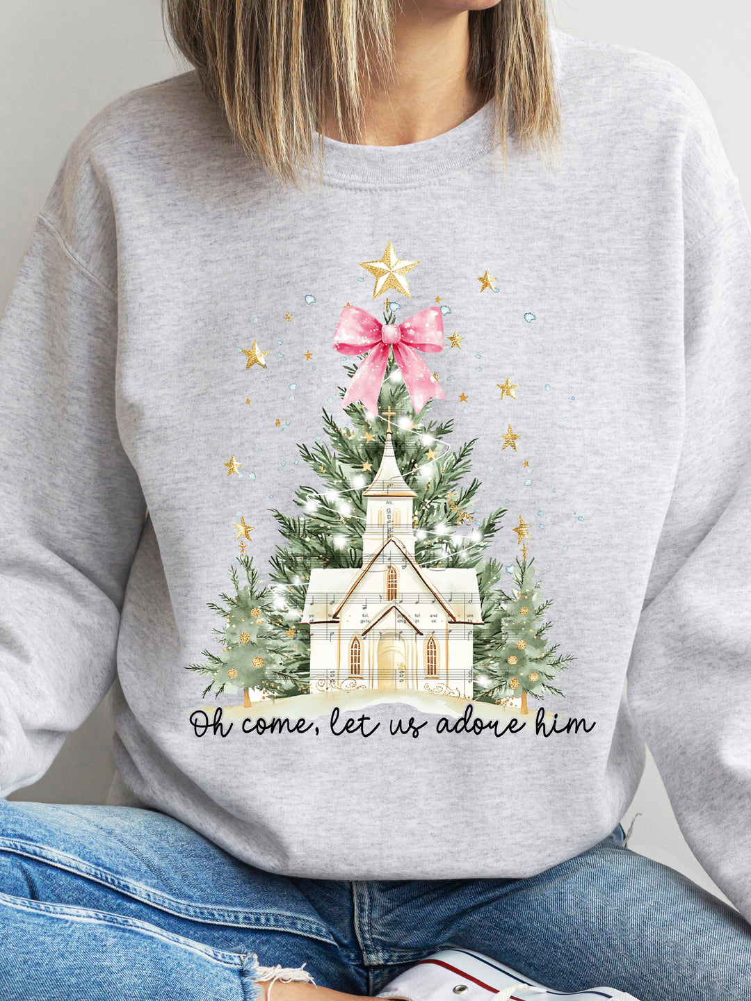 Gray sweatshirt with Christmas-themed design featuring a church and tree, worn by a person.